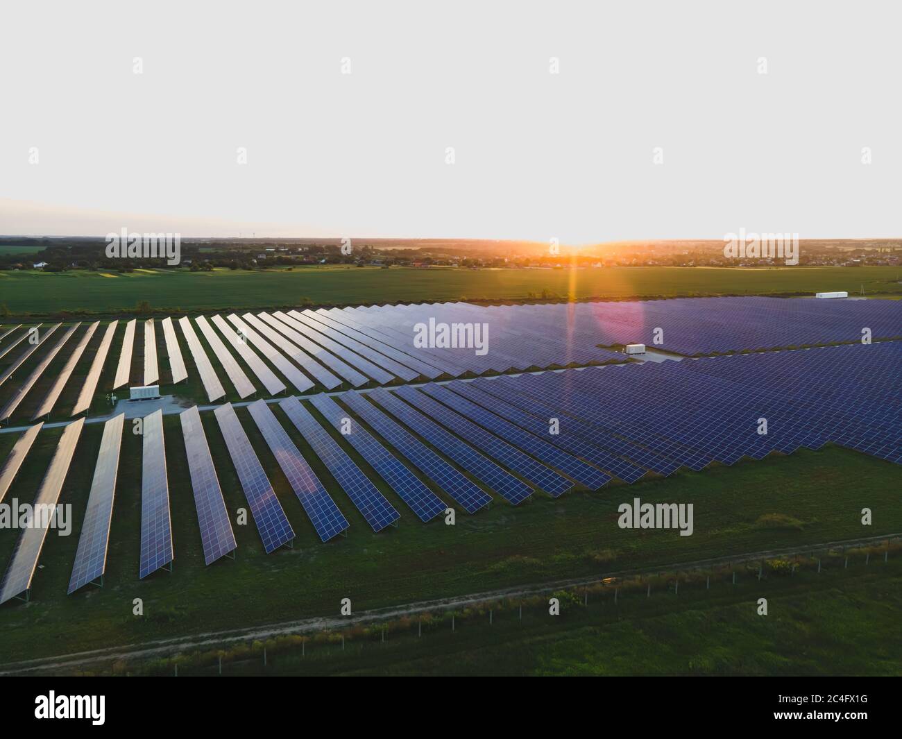 Aerial drone view of large solar panels at a solar farm at bright summer sunset. Solar cell power plants, colorful photo Stock Photo