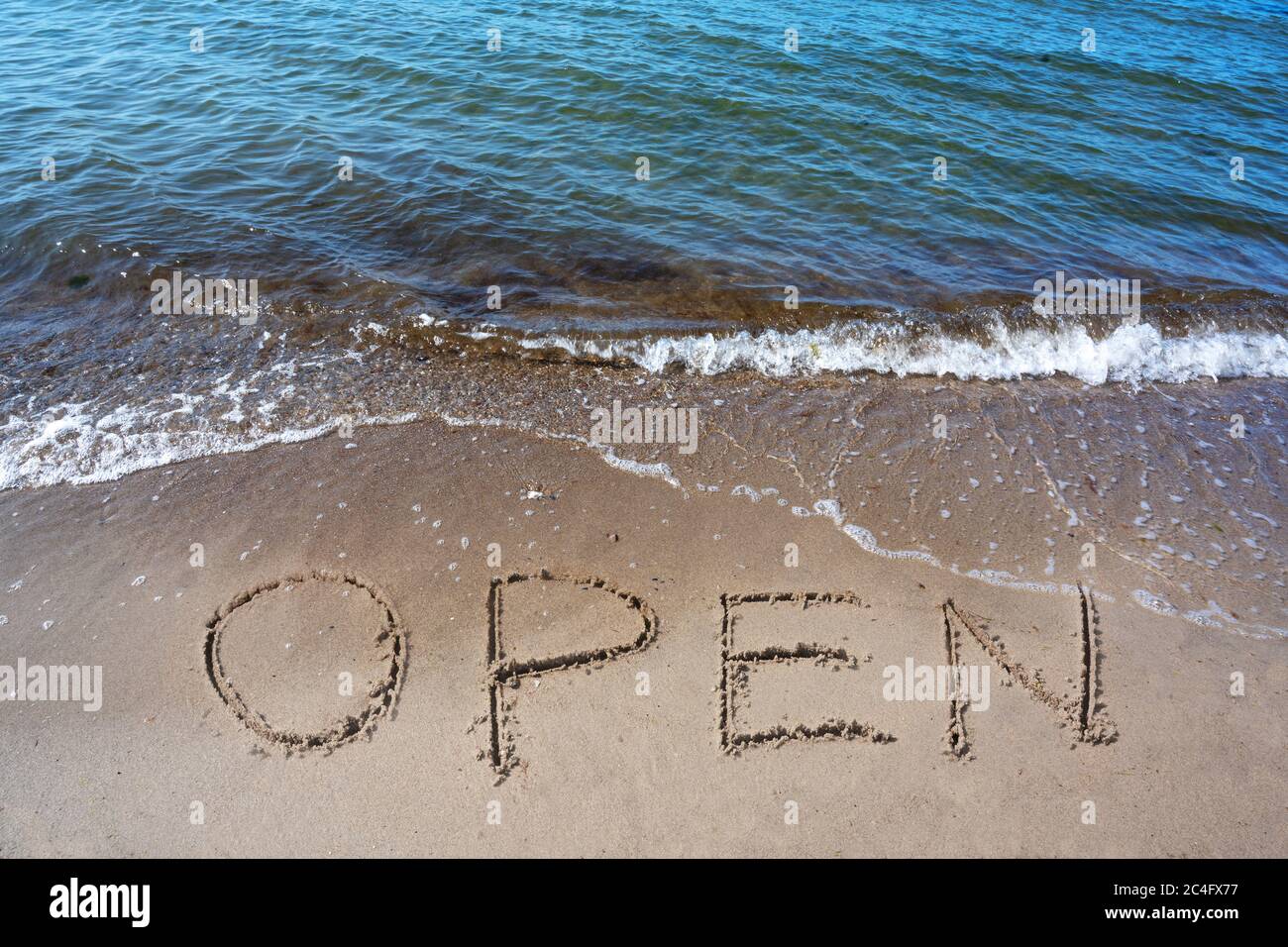 Word Open is written in the sand on the beach for the tourists, after the coronavirus pandemic, sea holidays are possible again, selected focus Stock Photo