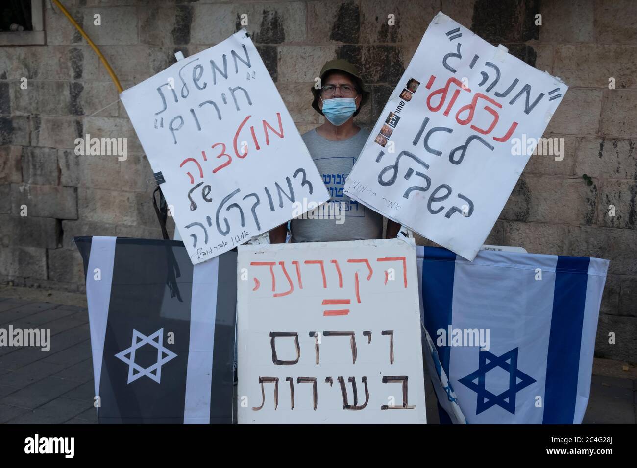 Jerusalem, ISRAEL 26th June 2020: A demonstrator holds placards with criticism quotes as hundreds of supporters of the so called Black Flag anti-corruption movement demonstrated outside the official residence of Prime Minister Benjamin Netanyahu, demanding he resign in light of the corruption indictments against him in Jerusalem, Israel. Credit: Eddie Gerald/Alamy Live News Stock Photo