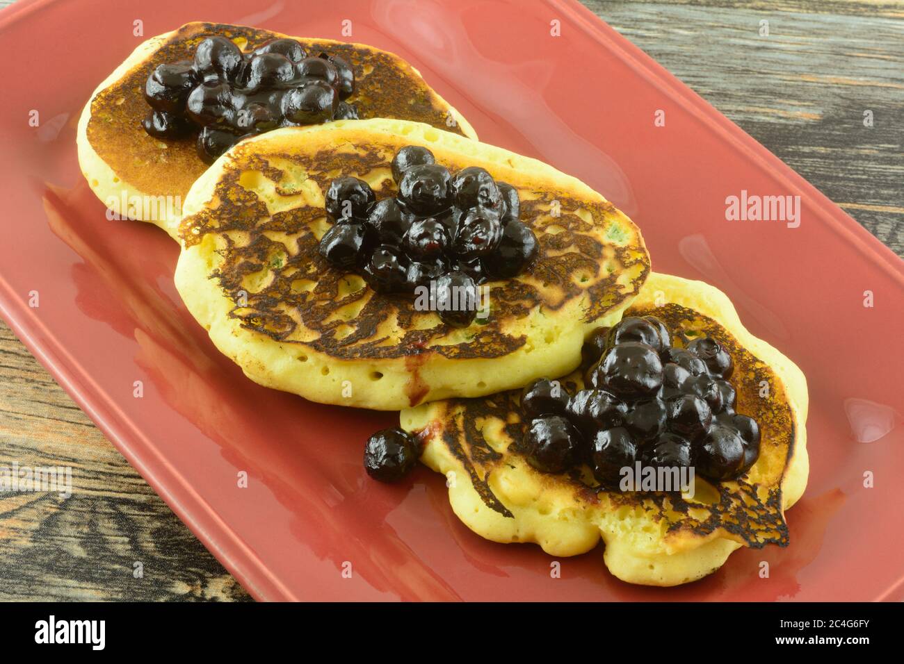 Cornmeal pancakes with jalapeno with blueberry sauce topping on red serving platter Stock Photo