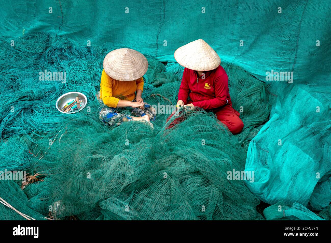 Thai Thuy District, Thai Binh Province, Vietnam - May 27, 2020: Two unidentified women are mending a fishing net in Thai Thuy District, Thai Binh Prov Stock Photo