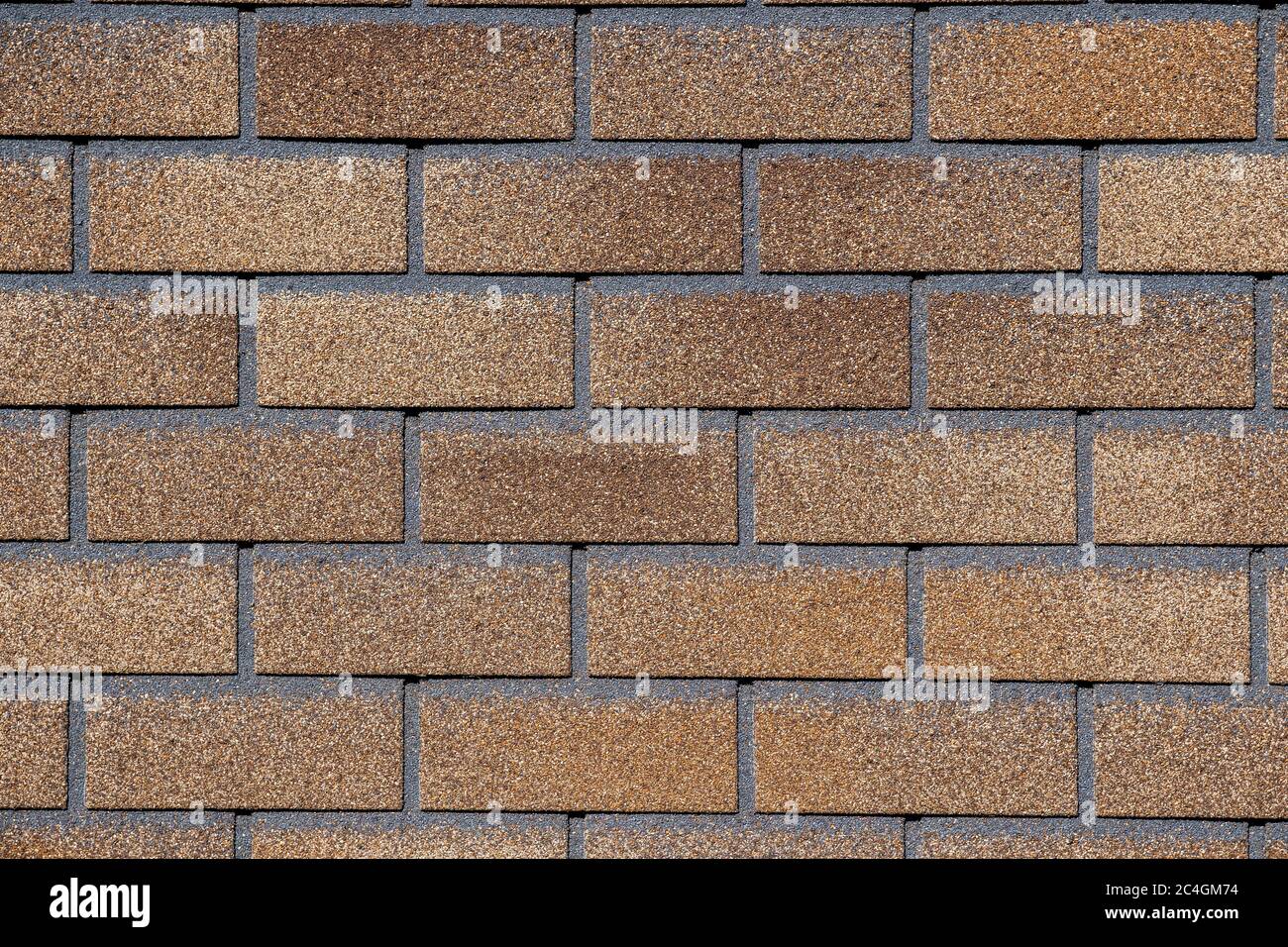 Dark brown and yellow surface of roofing tiles close up. Cover of shape of squares. Dark roof tile, grunge texture. Brick wall background. Stock Photo