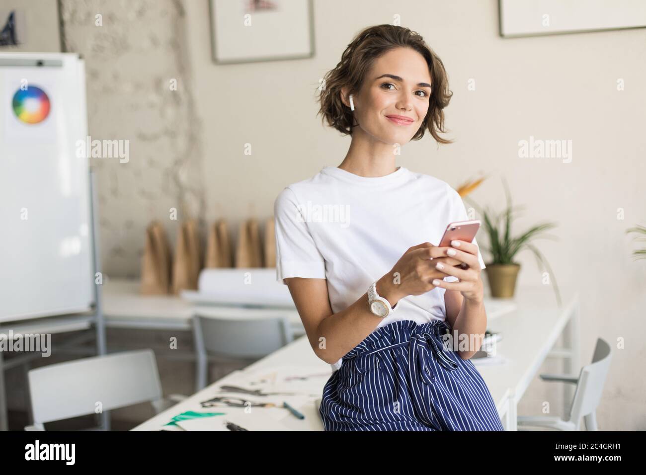 Young smiling woman with short curly hair in wireless earphones Stock Photo