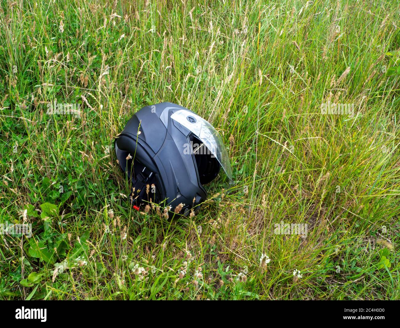 bike helmet in grass a motorcycle helmet lies with open visor in the green grass Stock Photo