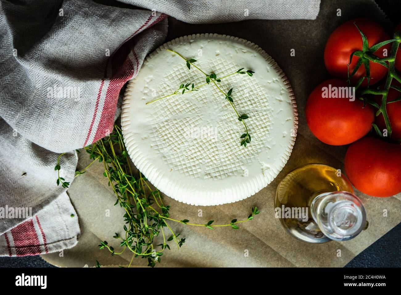 Georgian imeruli cheese with herbs, vegetable and oil on rustic background Stock Photo
