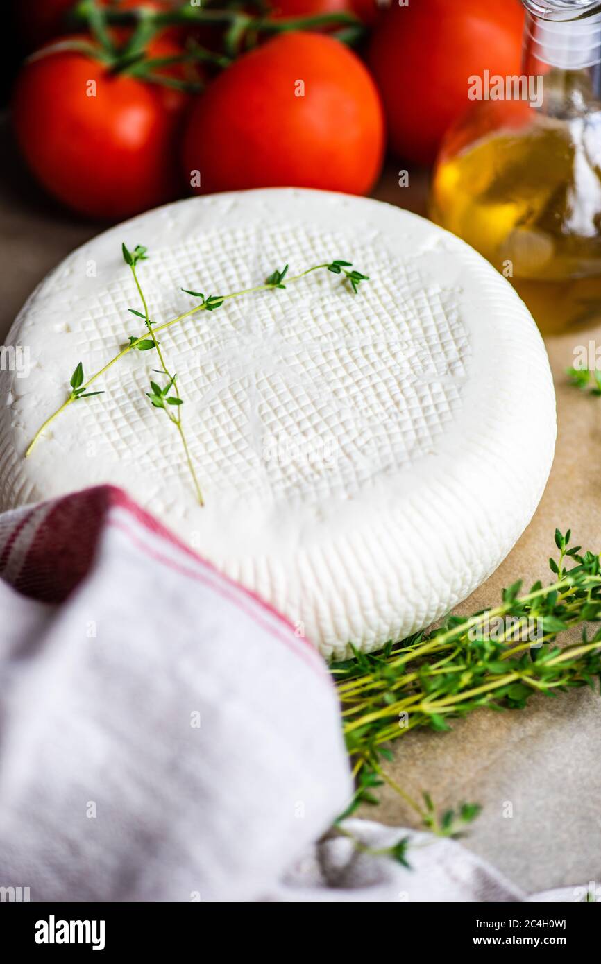 Georgian imeruli cheese with herbs, vegetable and oil on rustic background Stock Photo