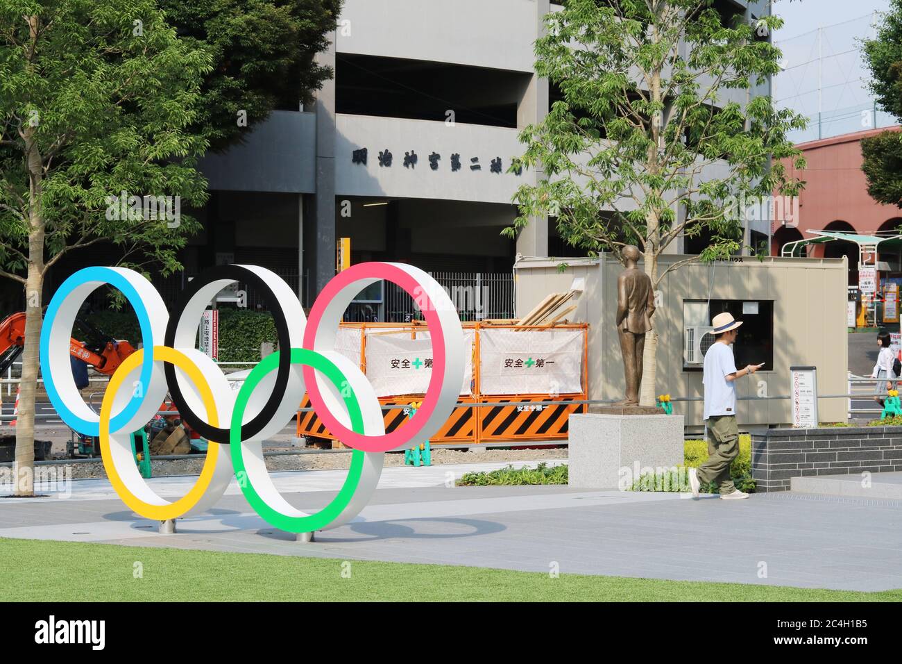 An Olympic Rings monument located outside the Japan Olympic Museum. A statue of Olympics-founder Pierre de Coubert & road works are in the background. Stock Photo