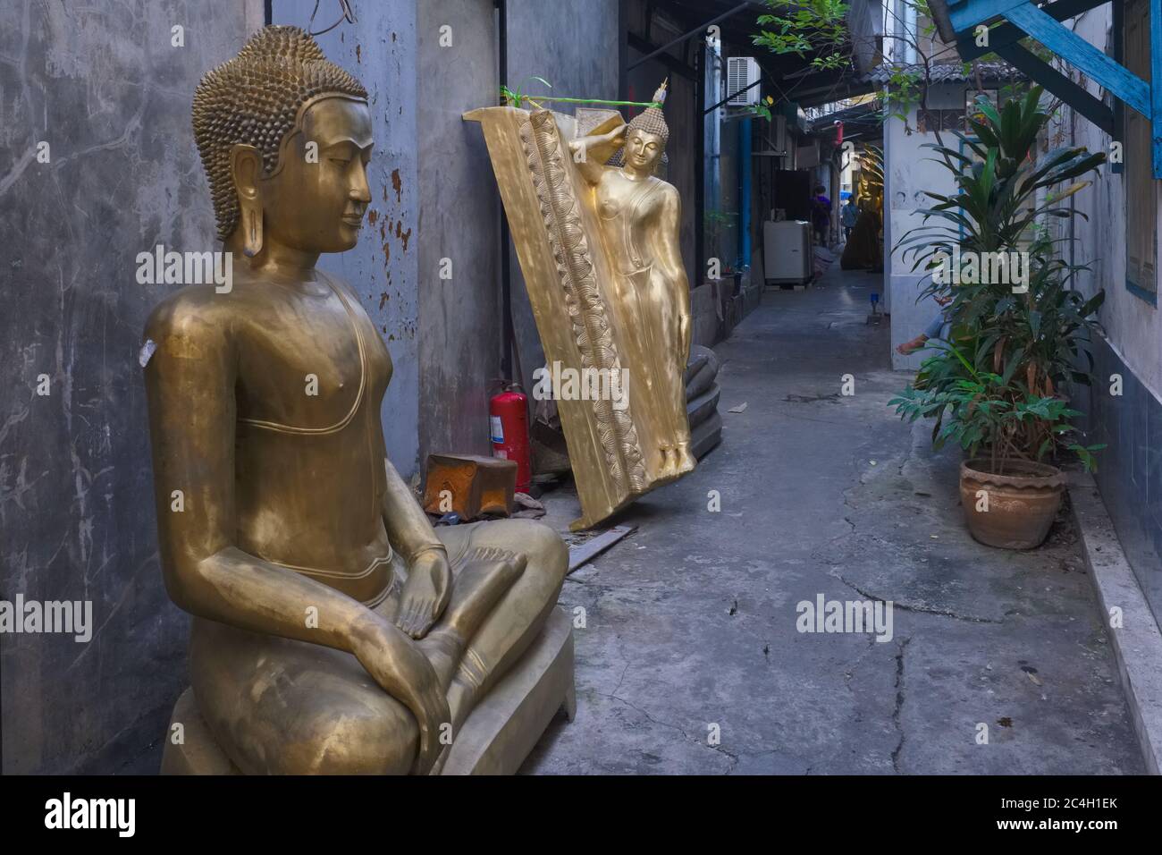 In a lane occupied by a factory producing religious objects off Bamrung Muang Road, Bangkok, Thailand, unfinished Buddha statues line the wall Stock Photo
