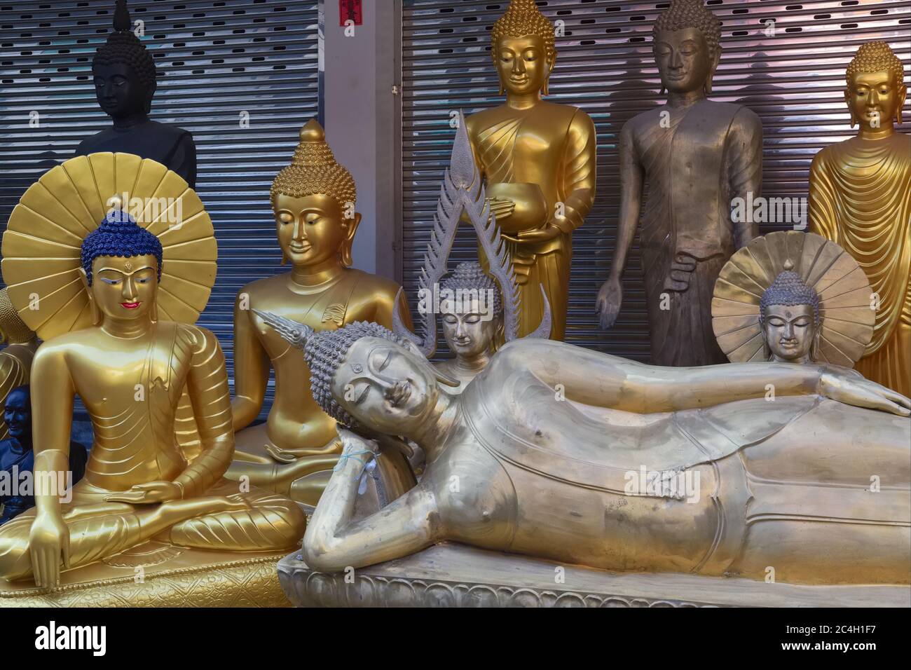 Buddha statues of various types - one reclining Buddha - in front of a factory outlet for religious objects in Bamrung Muang Road, Bangkok, Thailand Stock Photo