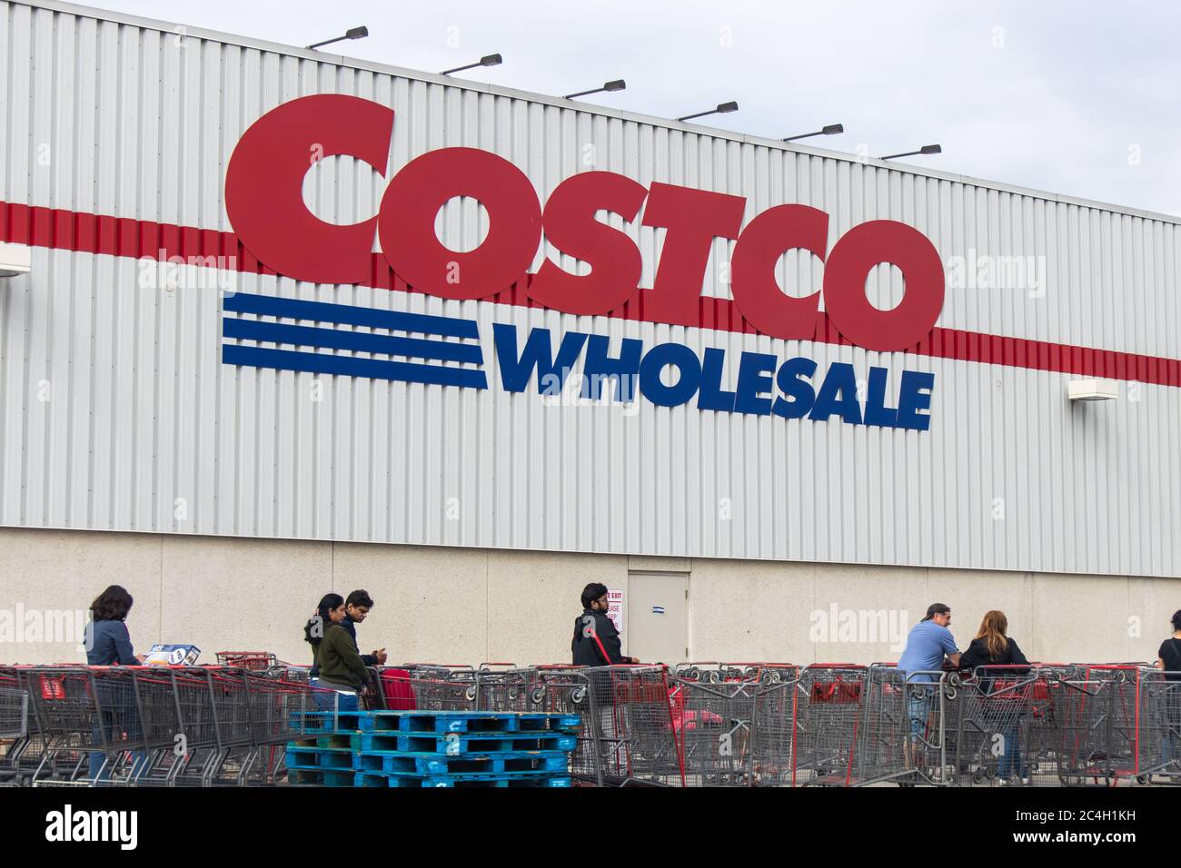 Costco Wholesale logo on a store as customers wait in-line during the COVID-19 coronavirus global pandemic. Stock Photo