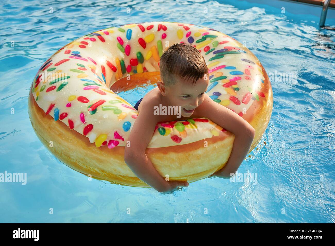 5 years old Boy in swimming pool on inflatable colorful ring Stock Photo