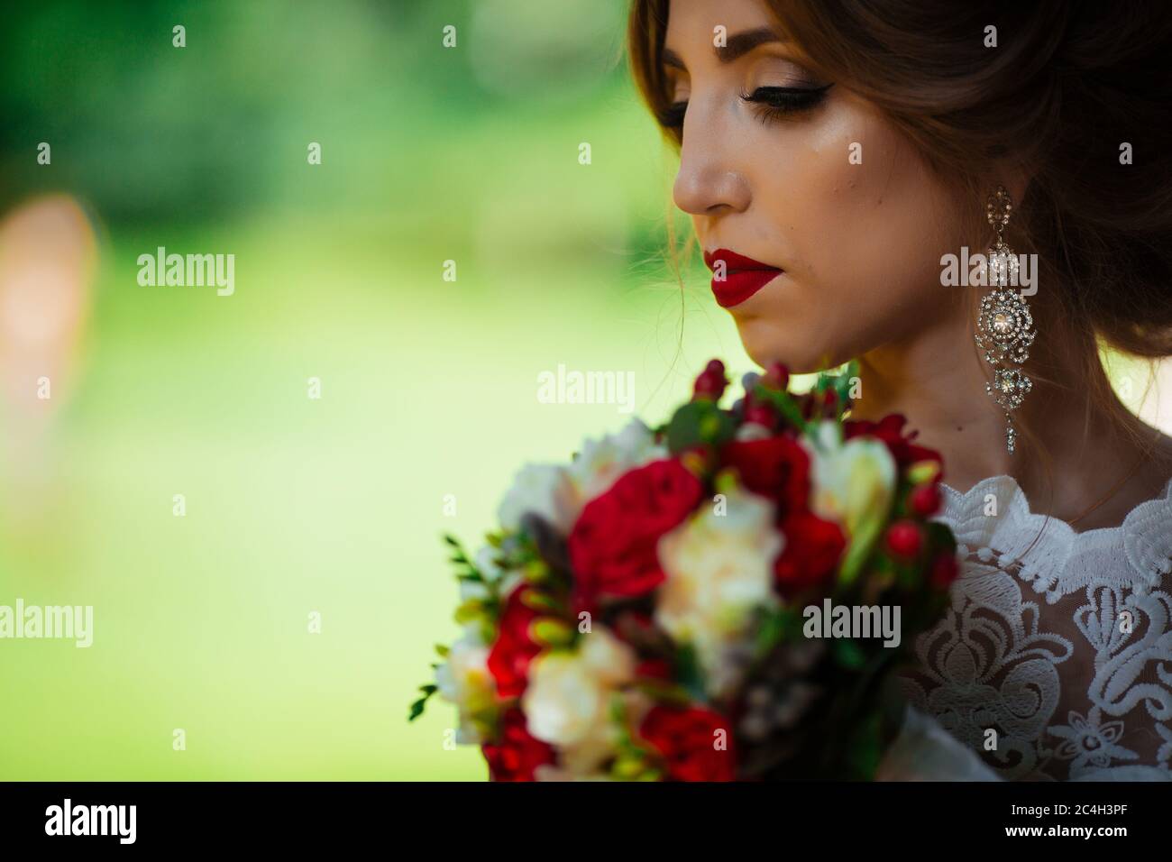 The bride in a white wedding dress holds a bouquet on a background of ...