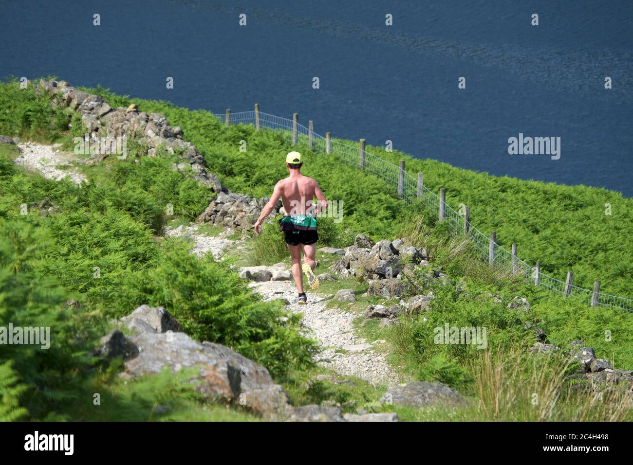 Fell runner descending towards Buttermere (lake) from Scarth Gap in the Lake District National Park and UNESCO World Heritage Site Stock Photo