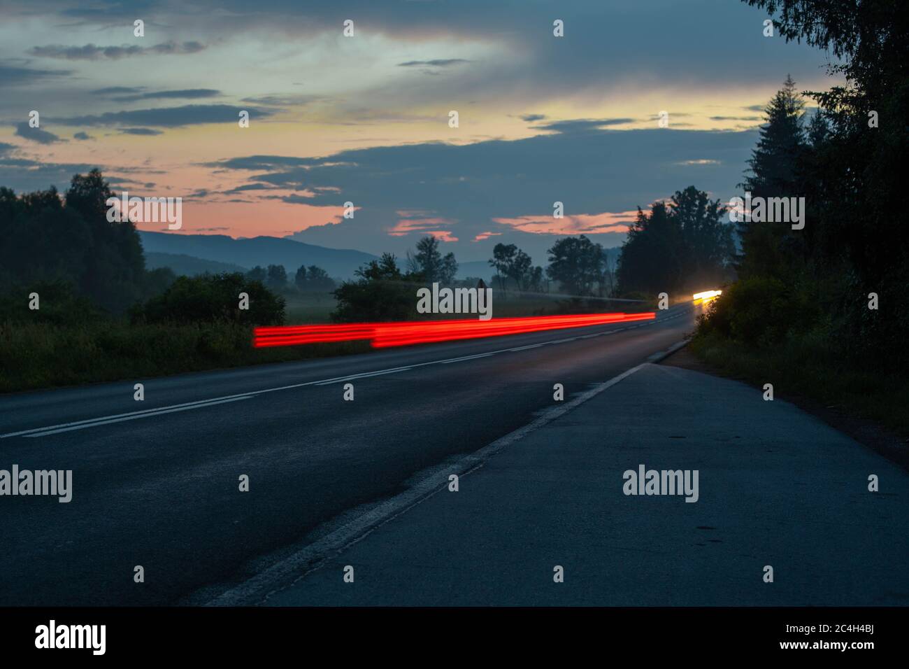 A highway road at dusk with blurred cars in motion after heavy rain ...