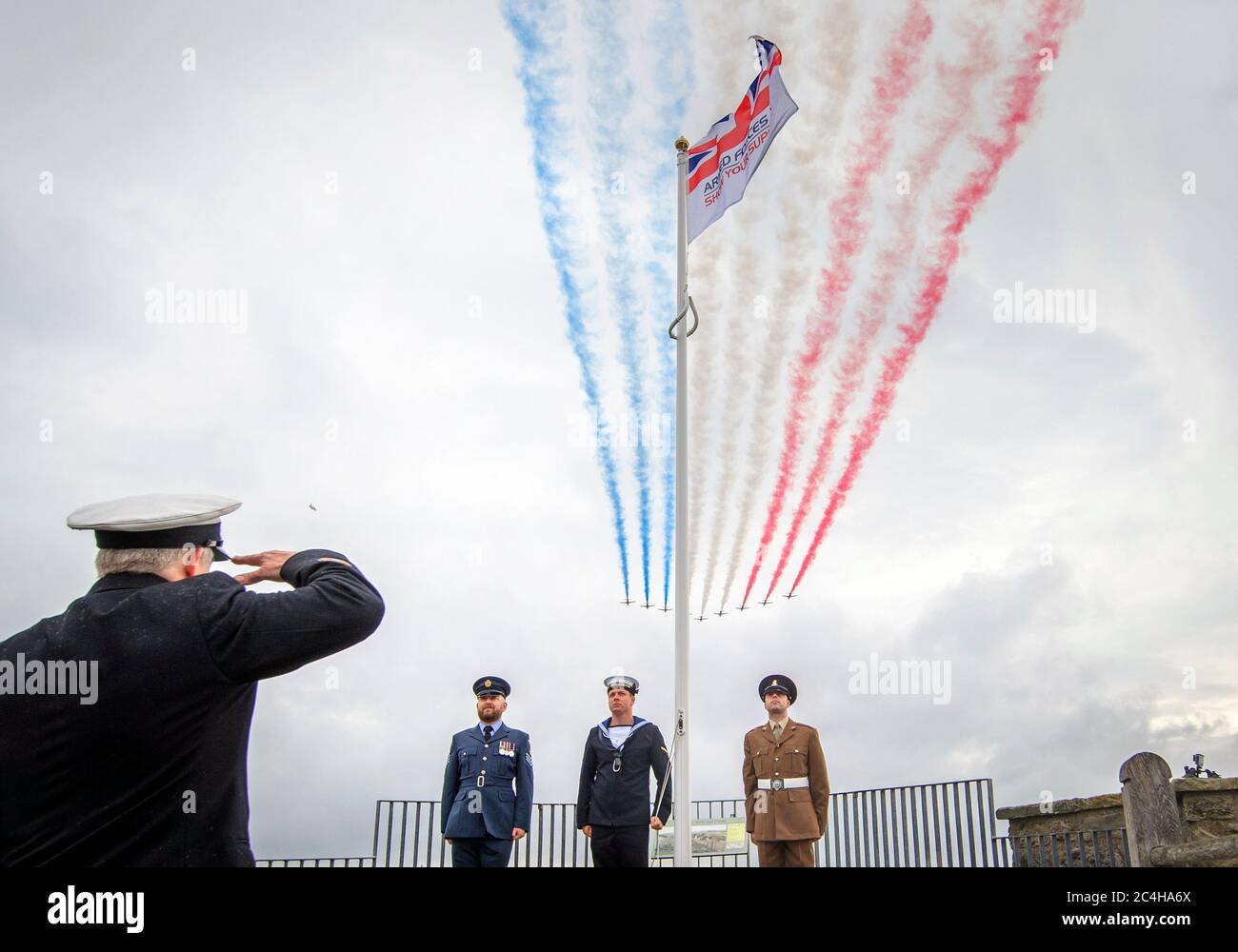 The Red Arrows perform a flypast over an Armed Forces Day flag in the grounds of Scarborough Castle in North Yorkshire, where celebrations for Armed Forces Day, were due to take place before being cancelled due to coronavirus. Stock Photo