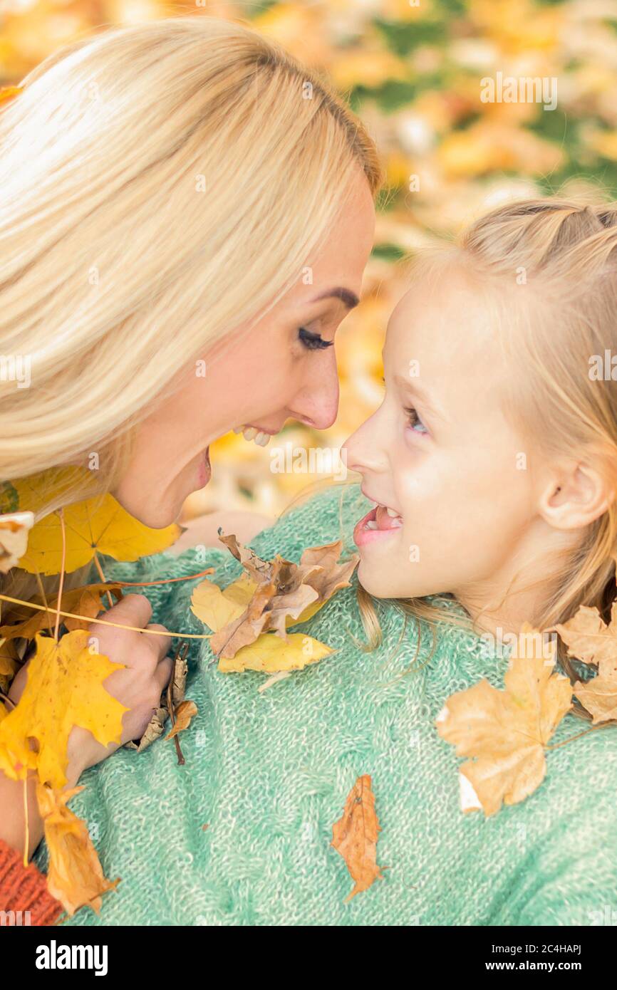 Beautiful young caucasian mother playing with her little child in the autumn park Stock Photo