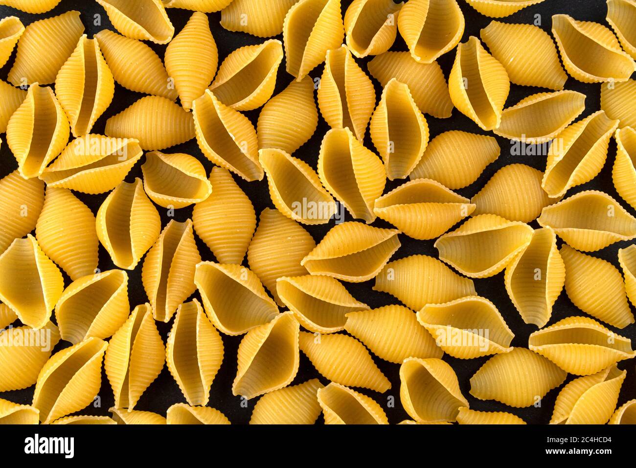 Dry shell pasta pattern on black background, top view Stock Photo