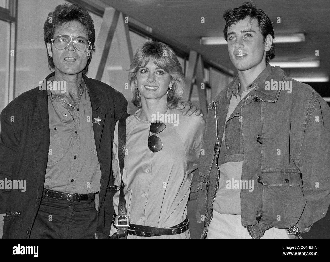 English Australian actress Olivia Newton John and husband Matt Lattanzi arriving at London's Heathrow Airport with British entertainer Sir Cliff Richards in September 1983. Stock Photo