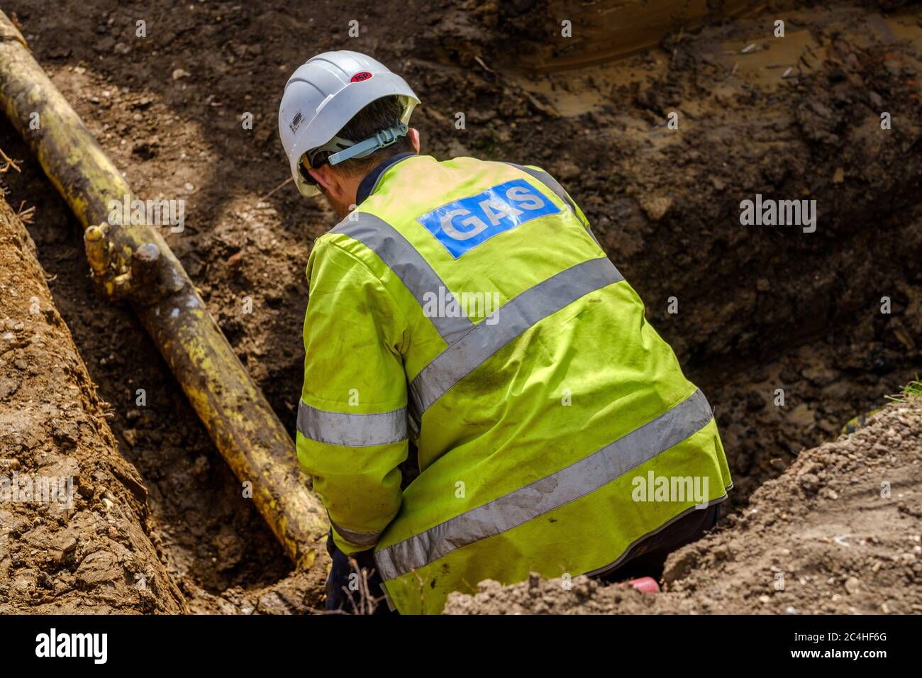 Gas engineer inspects pipe in trench on construction site Stock Photo