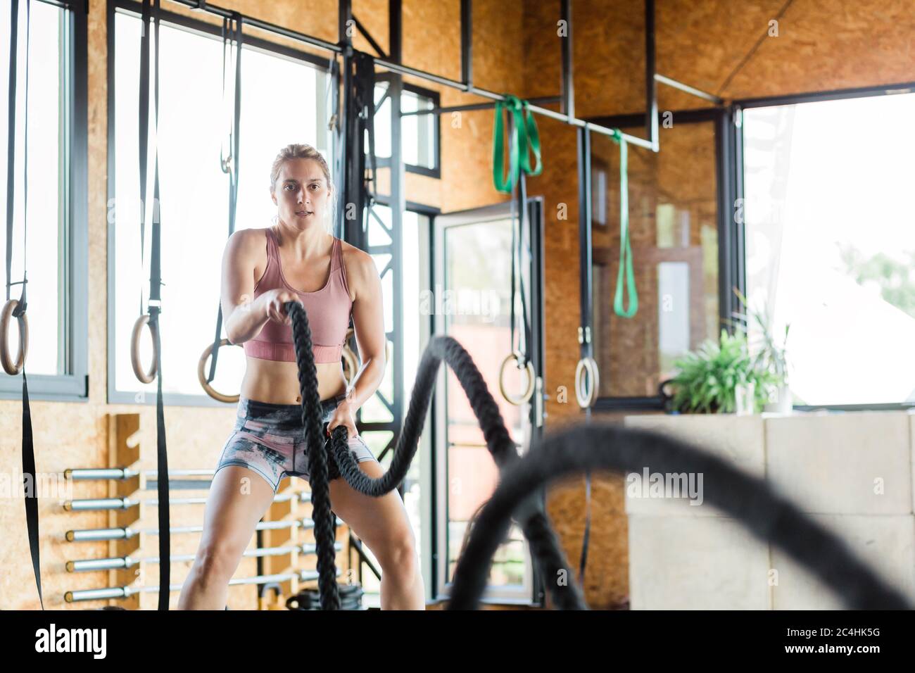 Young woman in the gym training crossfit on the ropes Stock Photo