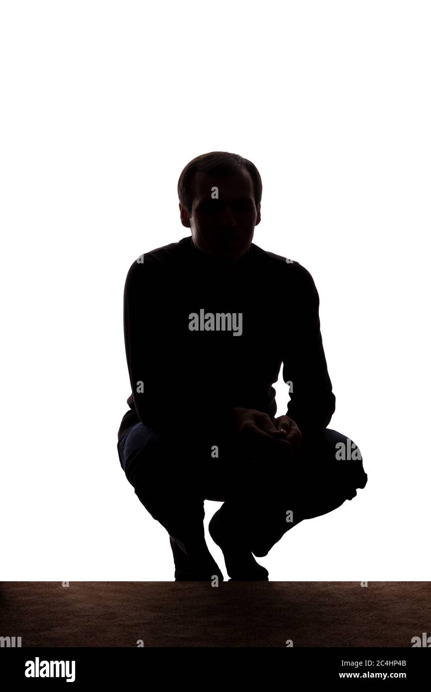 Portrait of a young man squatted down, front view - silhouette Stock Photo
