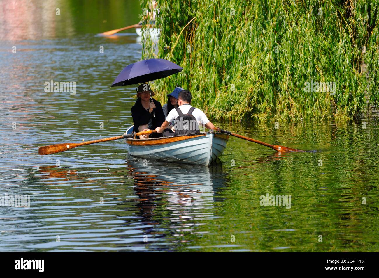 Tourists on a rowing boat in Knaresborough, use an umbrella for shade