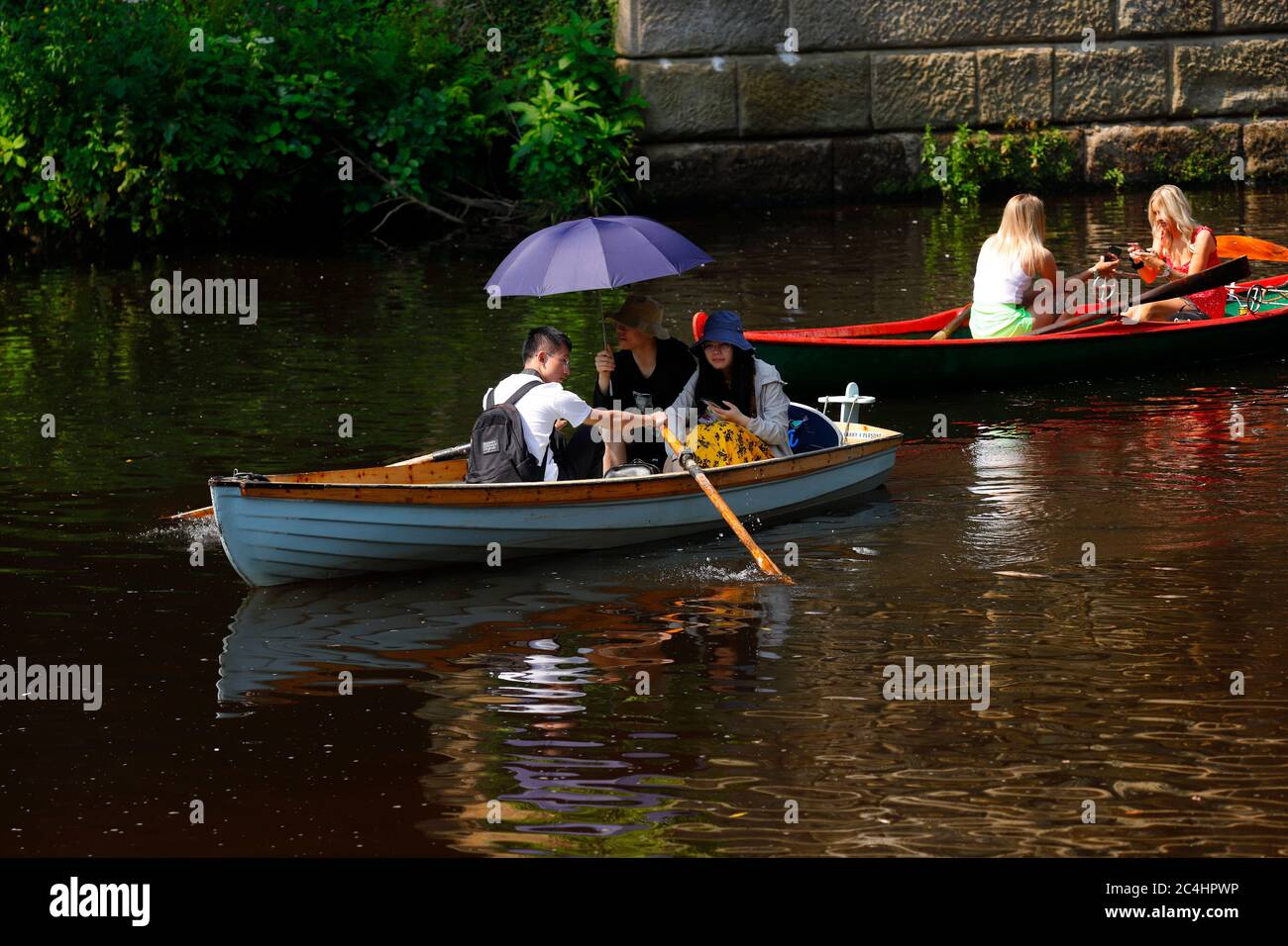 Tourists on rowing boats in Knaresborough, using an umbrella to take