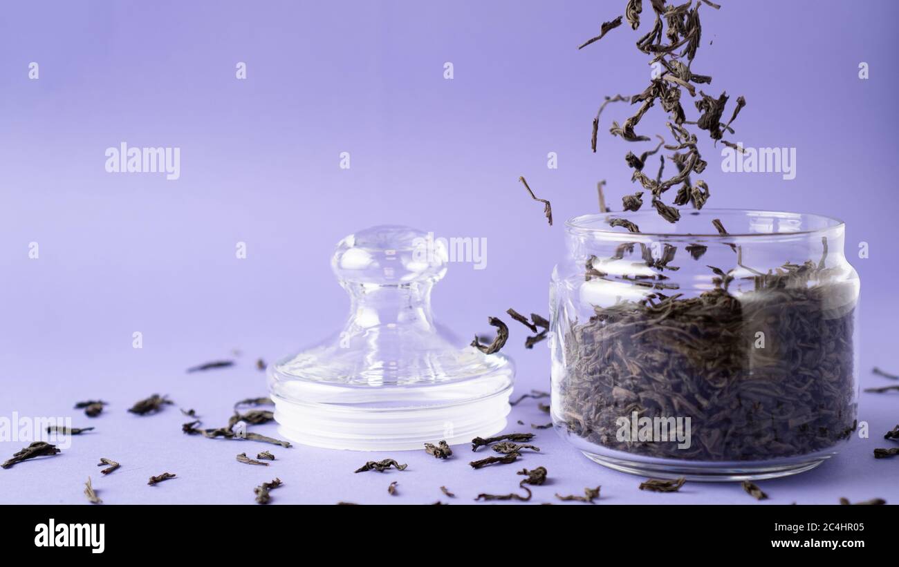 Large leaf black tea in glass jar. Flying tea leaves. Falling dried ...