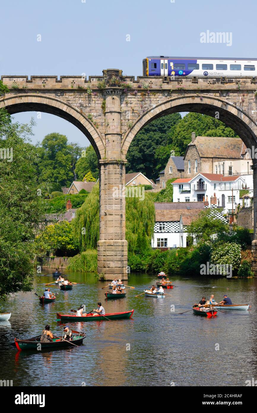 A Northern Rail train crosses Knaresborough Viaduct which spans the River Nidd. The river is popular with tourists using rowing boats for hire nearby Stock Photo