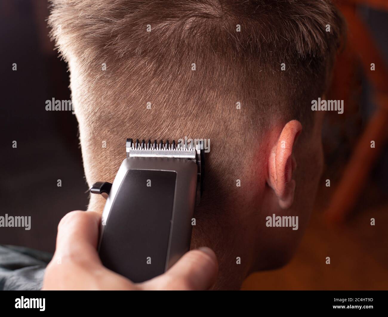 Men's haircut, master cuts r a young guy with a hair clipper close-up, hairdresser's tool. Stock Photo