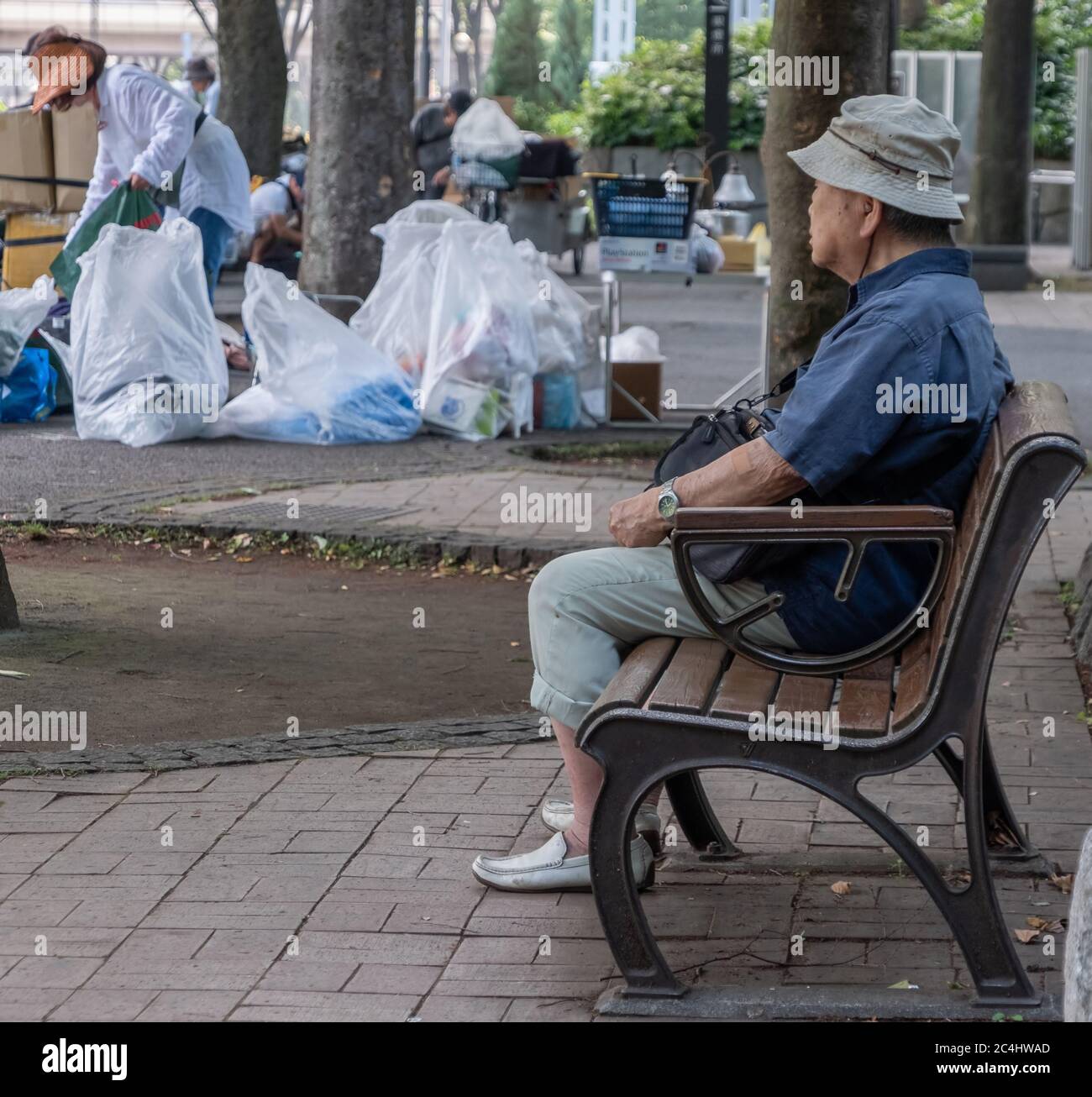 Old man sitting on a bench in a park, Shinjuku, Tokyo, Japan. Stock Photo