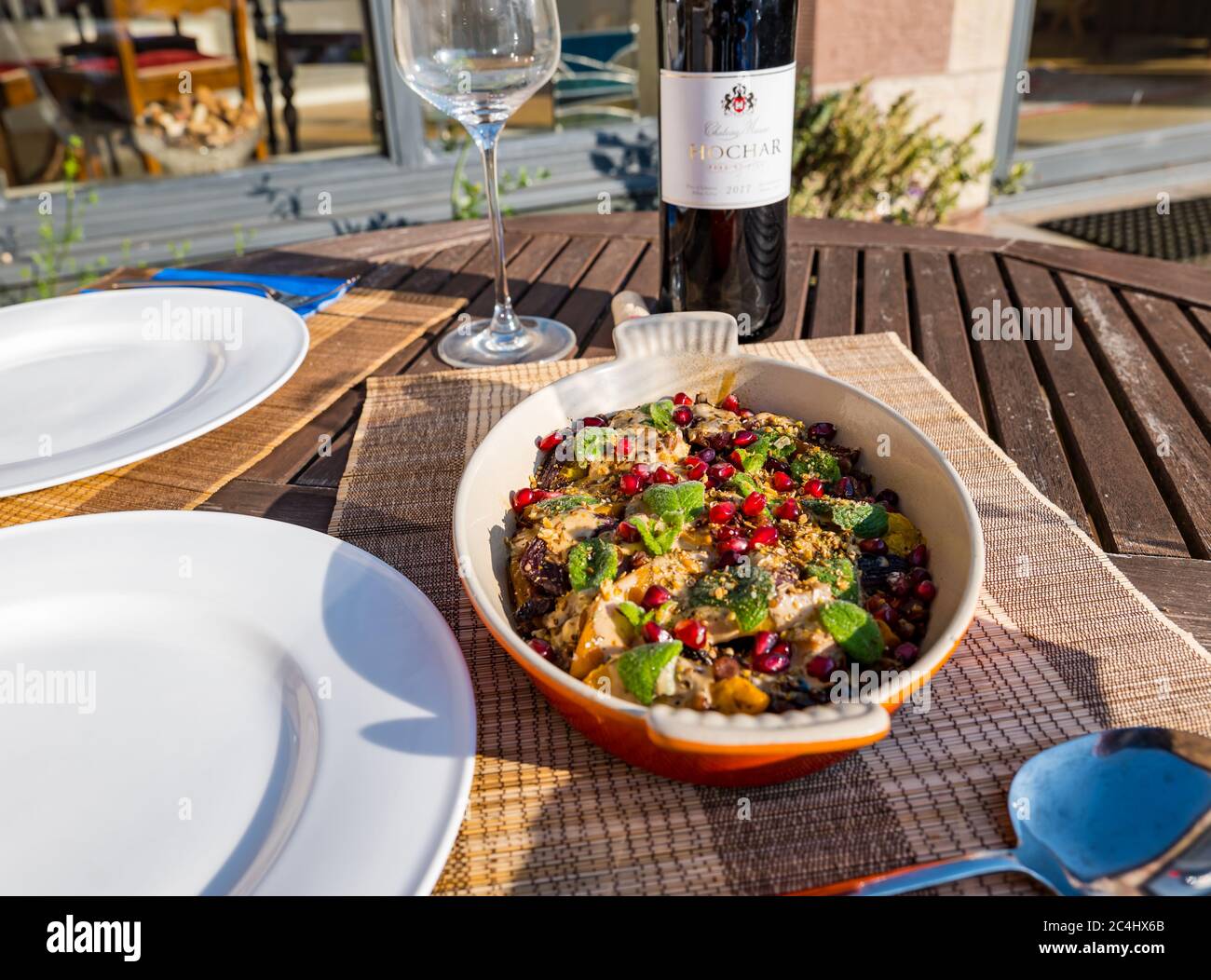 Middle Eastern roasted vegetable dish with butternut squash, pomegranate seeds; Lebanese red wine Chateau Musar Hochar from Bekaa Valley, UK Stock Photo