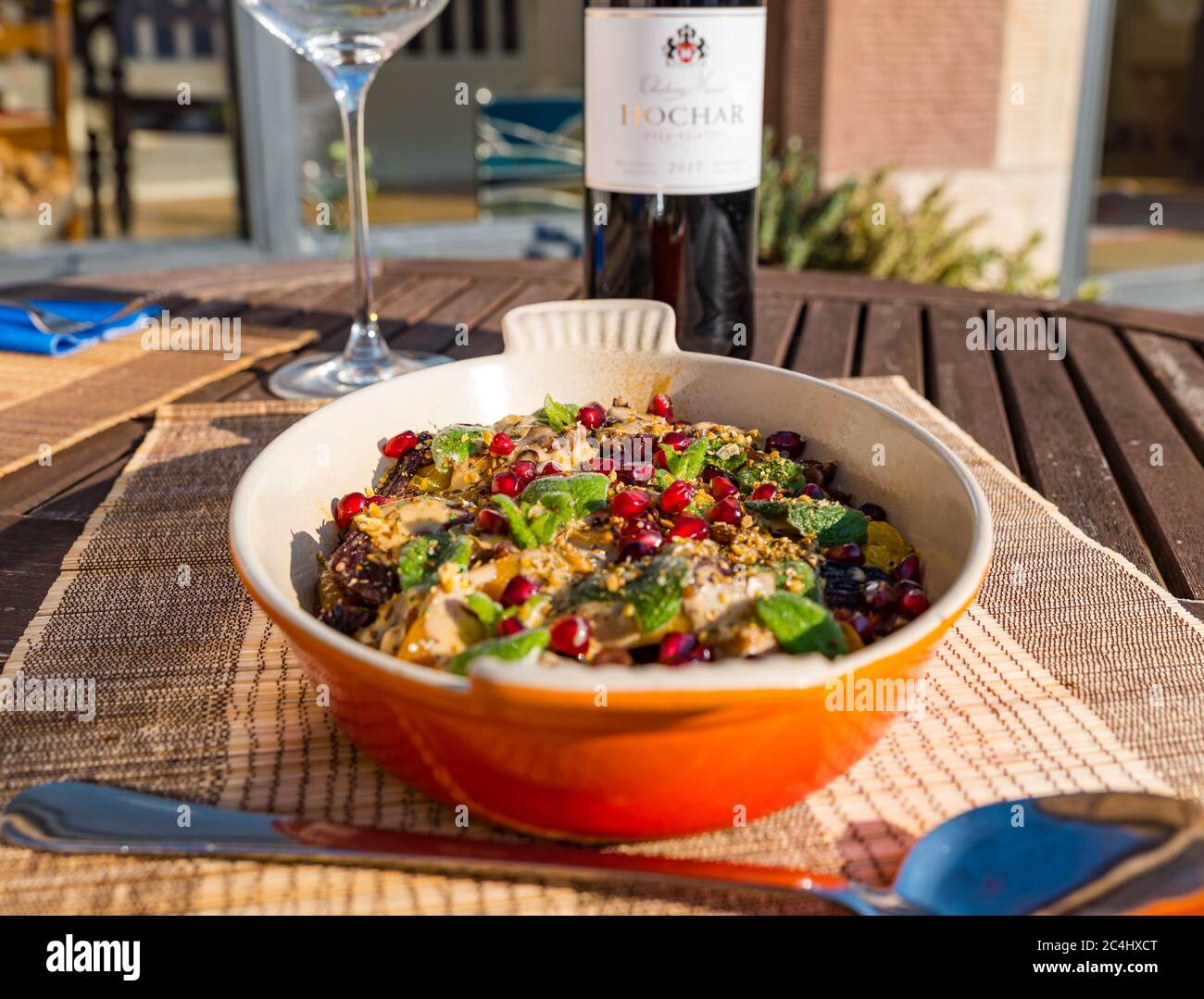 Middle Eastern roasted vegetable dish with butternut squash, pomegranate seeds; Lebanese red wine Chateau Musar Hochar from Bekaa Valley, UK Stock Photo