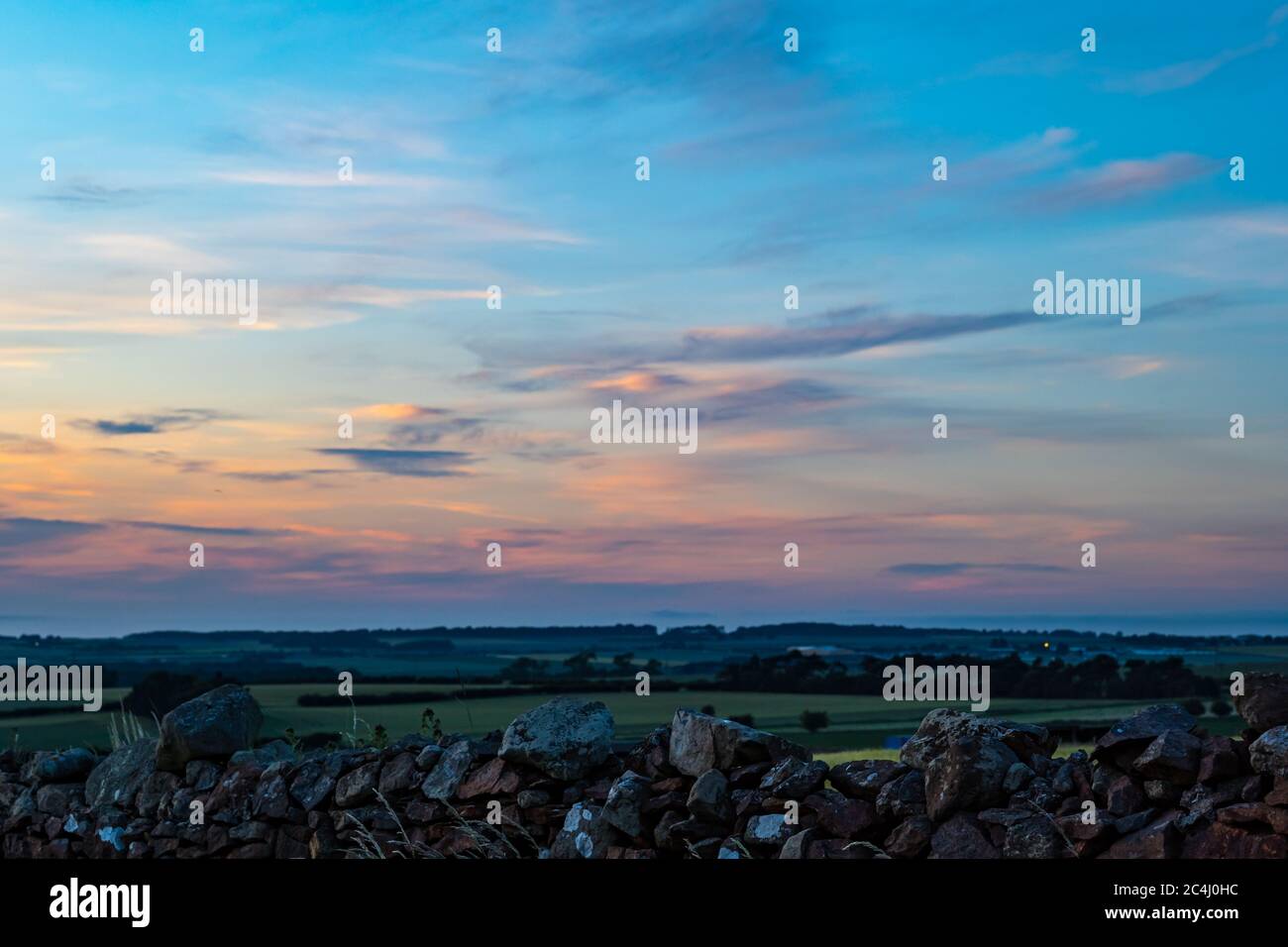Colourful pink sky at dusk overlooking agricultural landscape, East Lothian, Scotland, UK Stock Photo