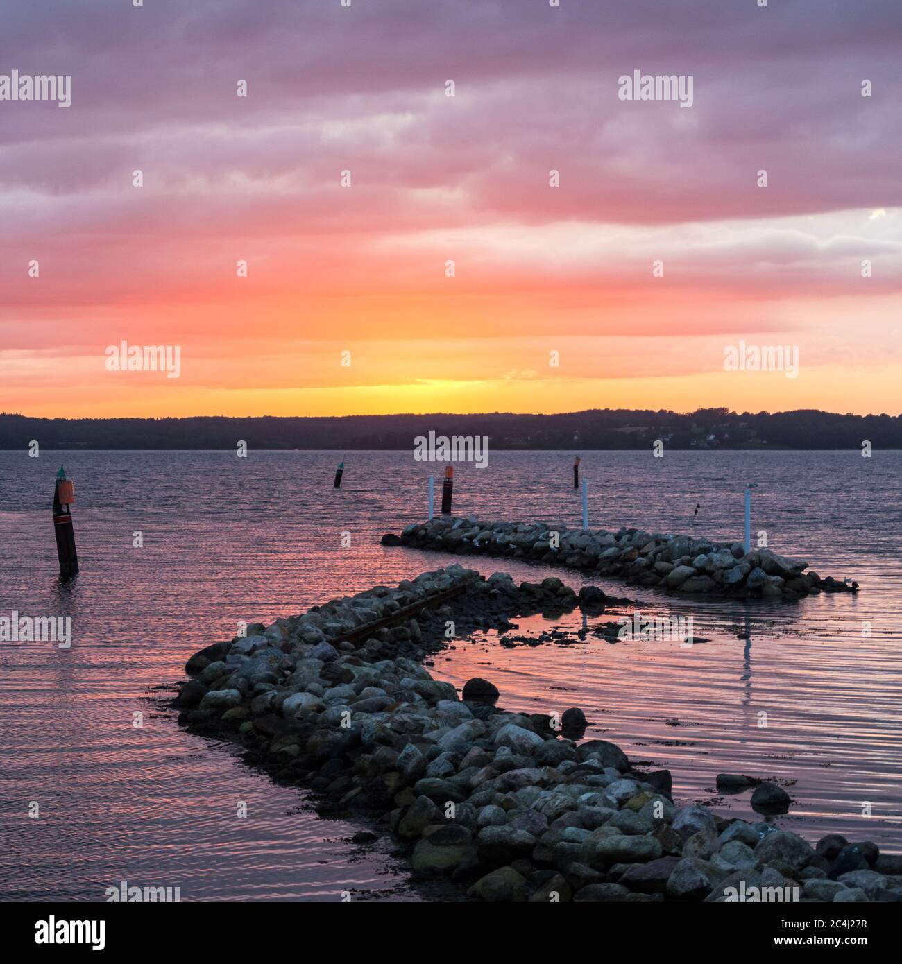 Breakwater rocks at the Baltic Sea during dramatic colourful sunset Stock Photo