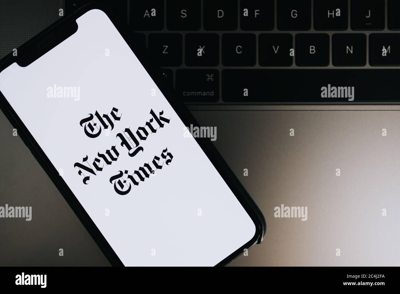 Hands holding iPhone X with The New York Times logo on the screen. Stock Photo