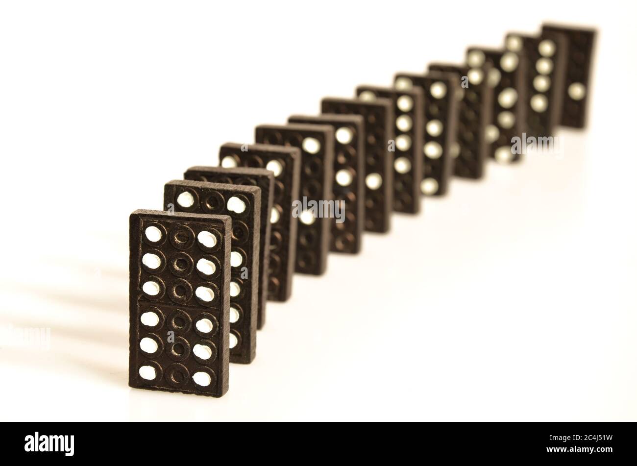Black domino pieces standing in line in front of white background Stock Photo