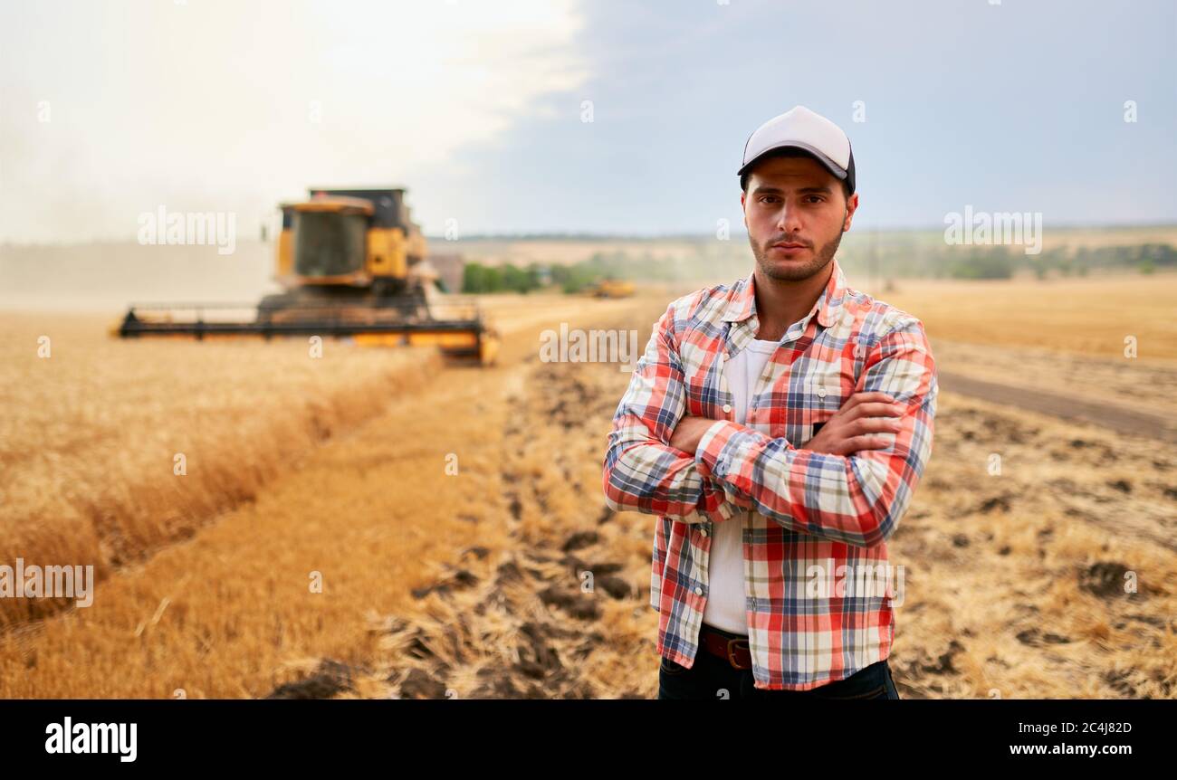 Happy farmer proudly standing in a field with arms crossed on chest