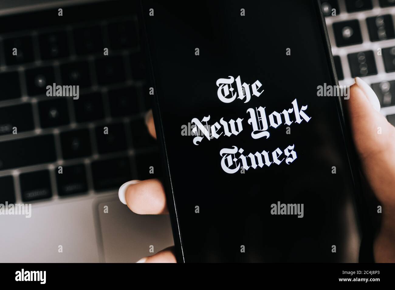 Hands holding iPhone X with The New York Times logo on the screen Stock