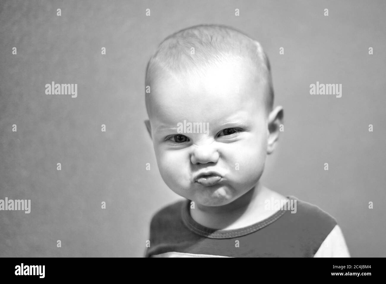 Portrait of a funny little boy who grimaces, black and white photo Stock Photo