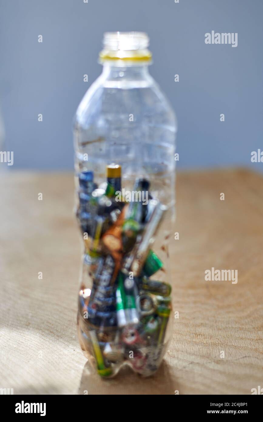Used batteries in a plastic bottle on a wooden background, the topic of