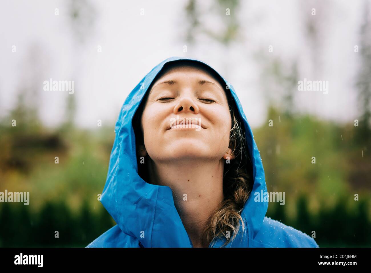 woman stood in the rain smiling with rain drops on her face Stock Photo