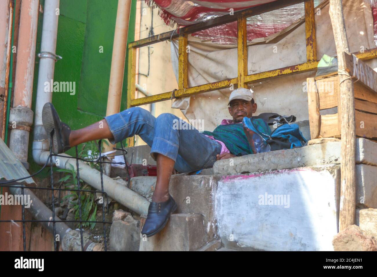 Antananarivo, Madagascar 05/17/20: A homeless man lies on the side of the street and tries to sleep. Economic ruin and unemployment as consequences of Stock Photo