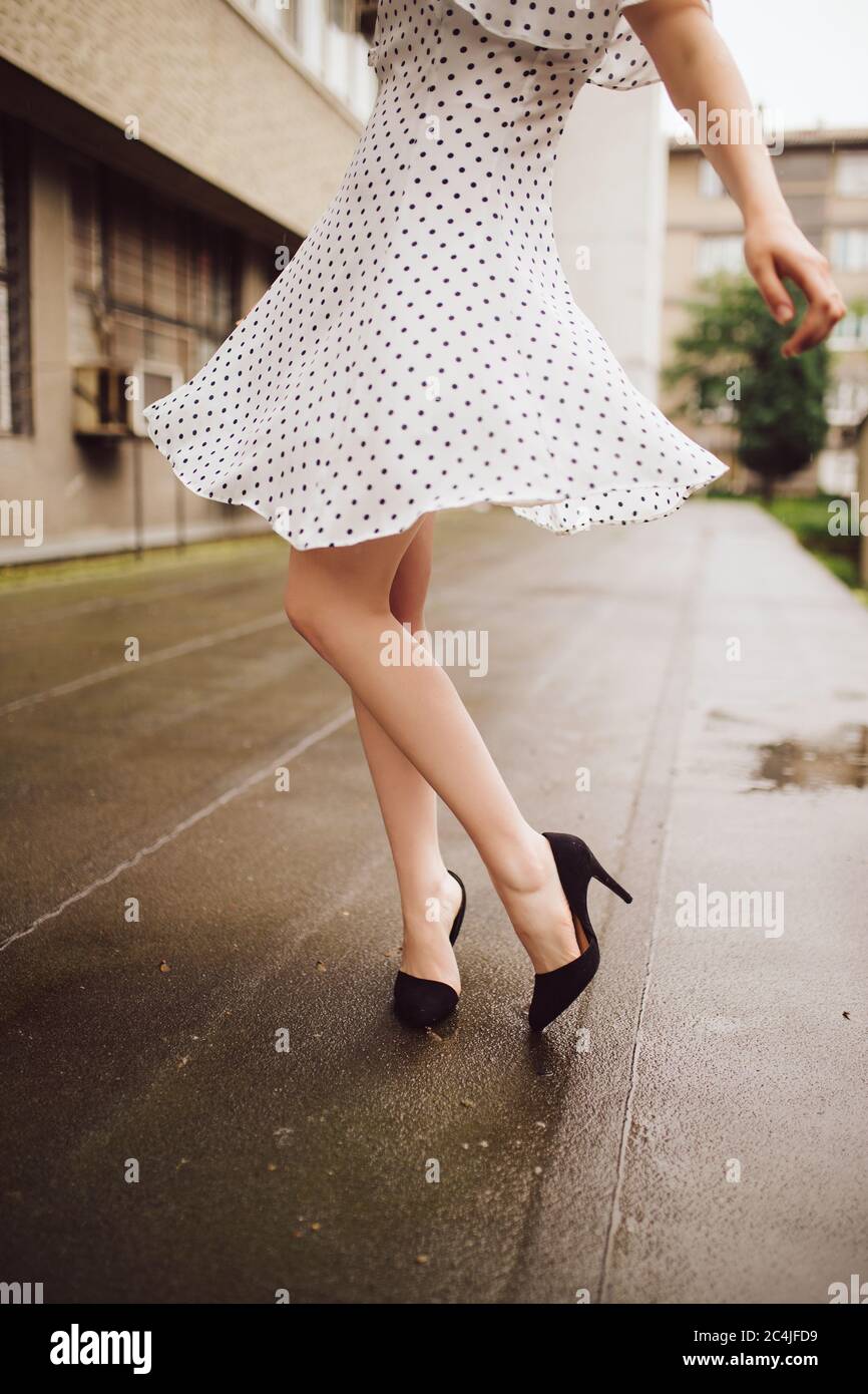 Woman in polka dot dress dancing in the rain Stock Photo