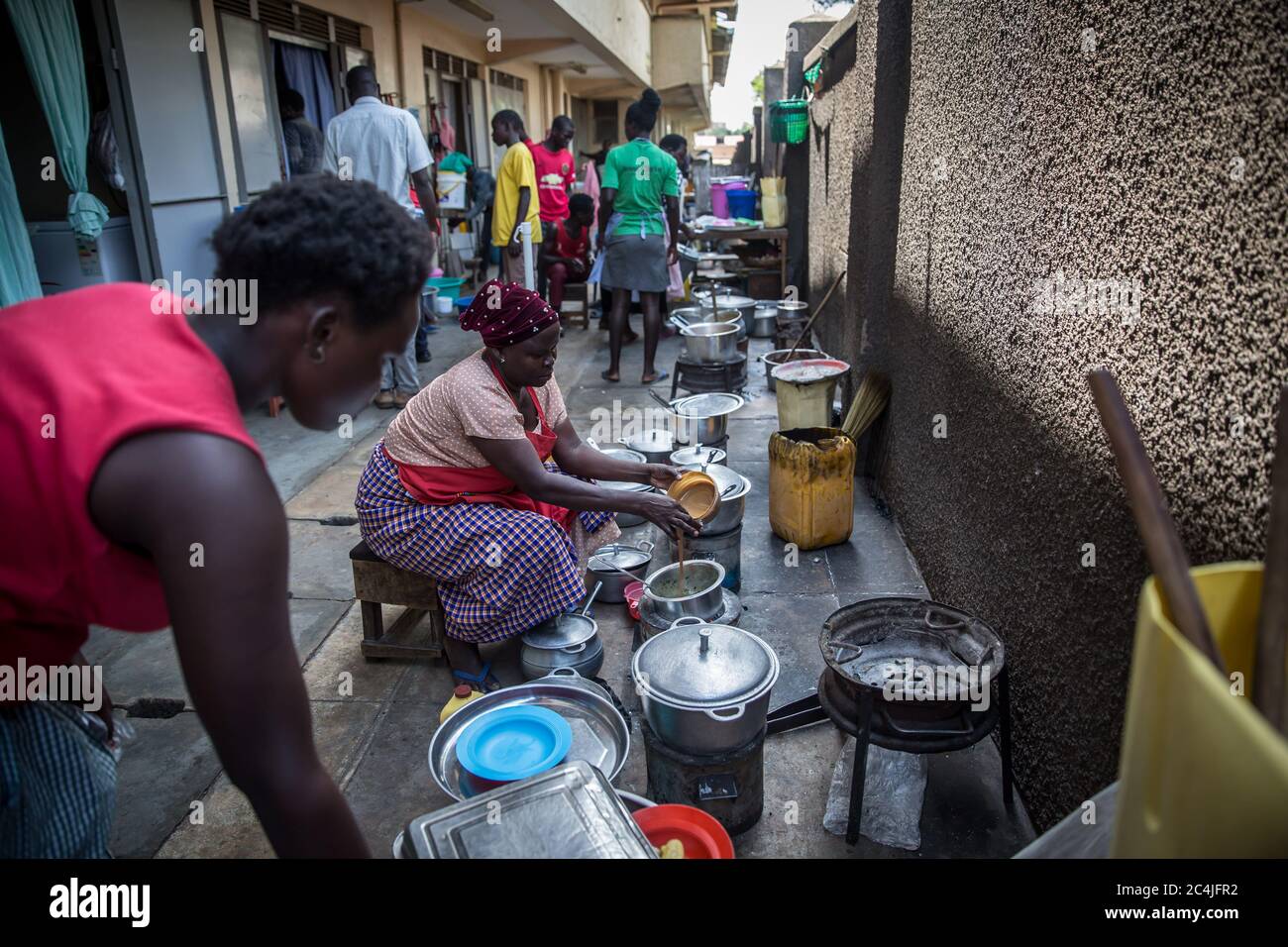 Women are seen cooking food for street children behind the main market in Gulu, northern Uganda, during Uganda's coronavirus lockdown.Hundreds of street children in Gulu, northern Uganda, have been put in danger, with nowhere to go during a coronavirus-related lockdown, which includes a 7pm curfew. Millions of street children across the world are particularly vulnerable during the pandemic. Stock Photo
