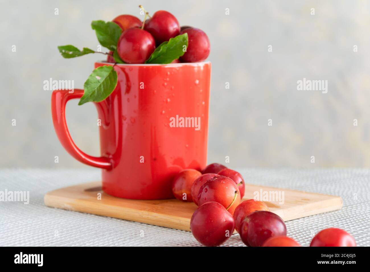 Fresh raw plums in red cup, healthy sweet food Stock Photo