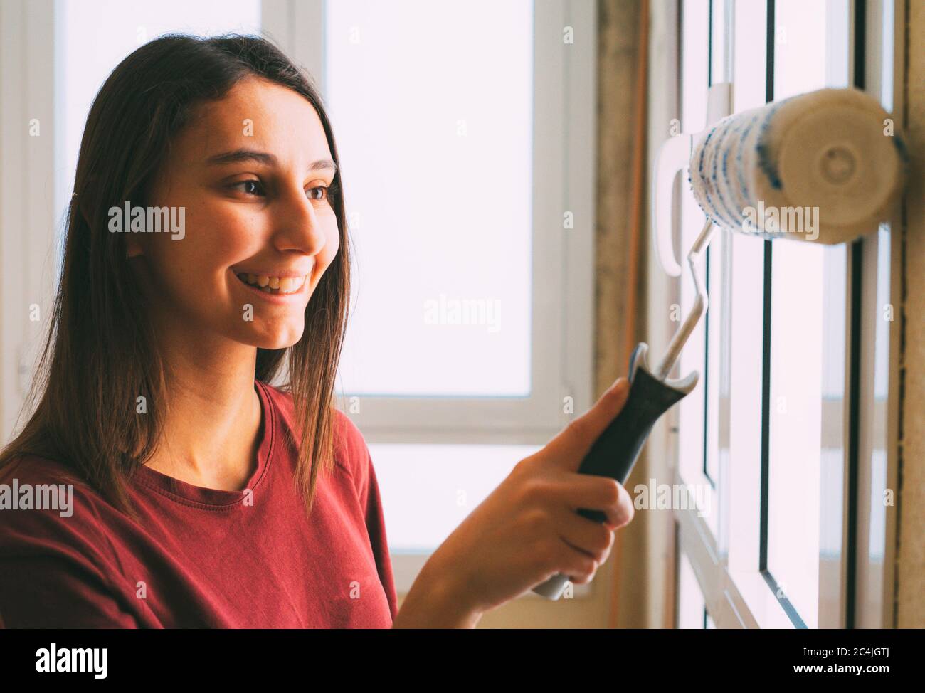 Female painter painting her house with a paint roller brush. Concept of