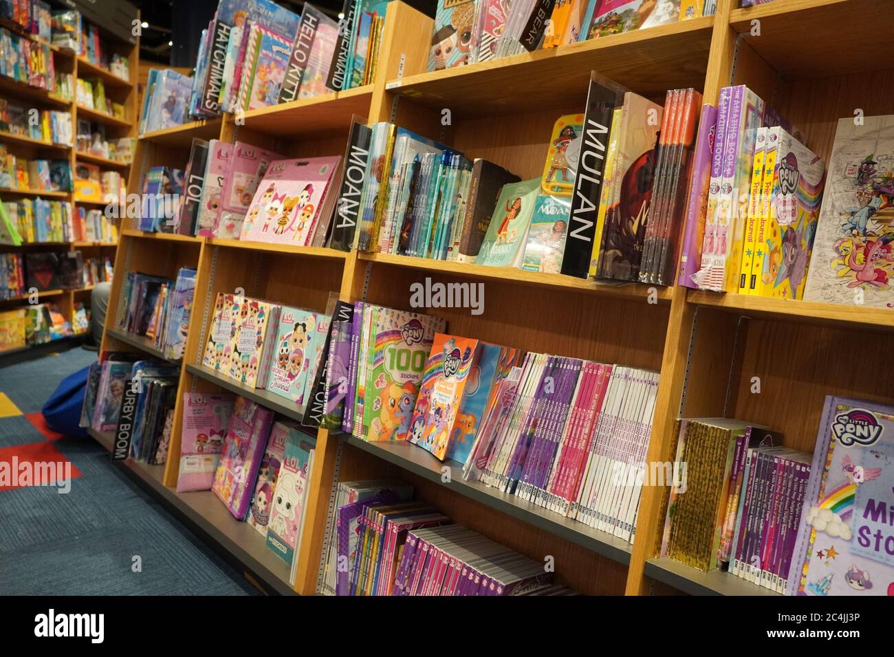 Children drawing and coloring books on shelves in a bookstore for sale. Library kids books section. Variety of Books For Sale On Bookshelf In Library. Stock Photo