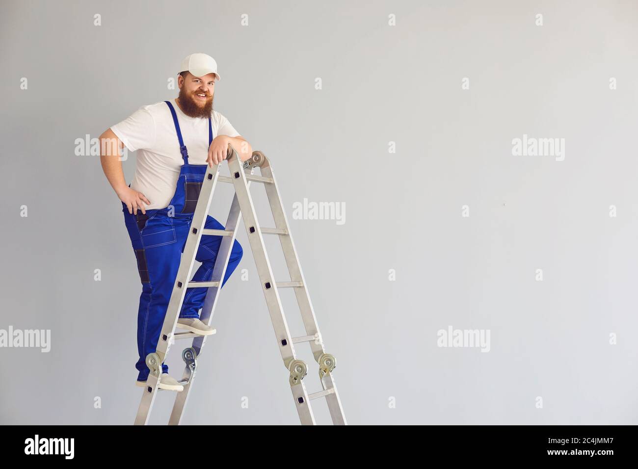 Builder funny man worker.Delighted male constructor on metal ladder. Stock Photo