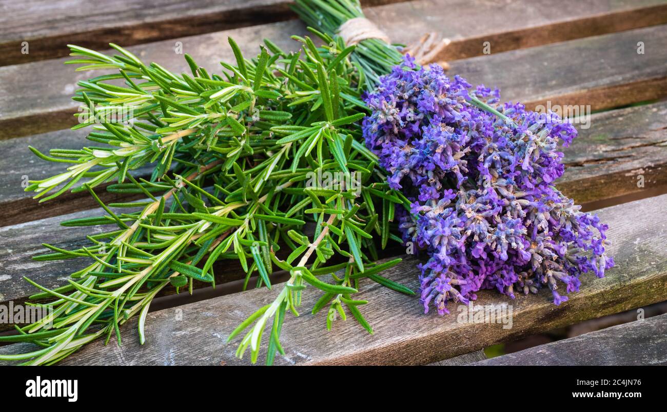 A bunch of fresh lavender and rosemary on a wooden garden table. Stock Photo